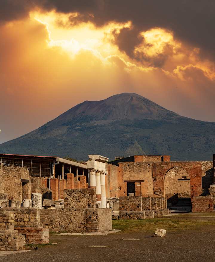 Pompeii at twilight with the sun shining through the clouds.