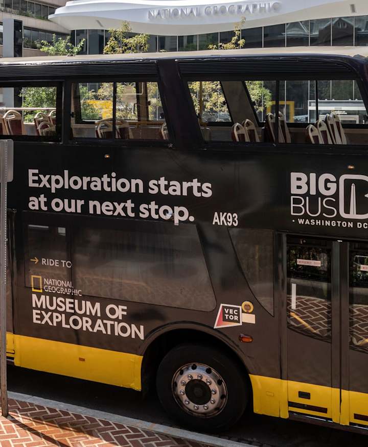 Big Bus with National Geographic Museum branding, parked outside the Museum of Exploration.