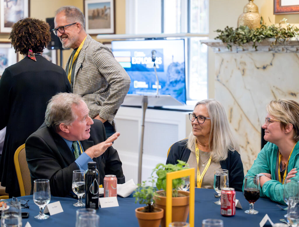 A National Geographic Explorer talking with others at a table.