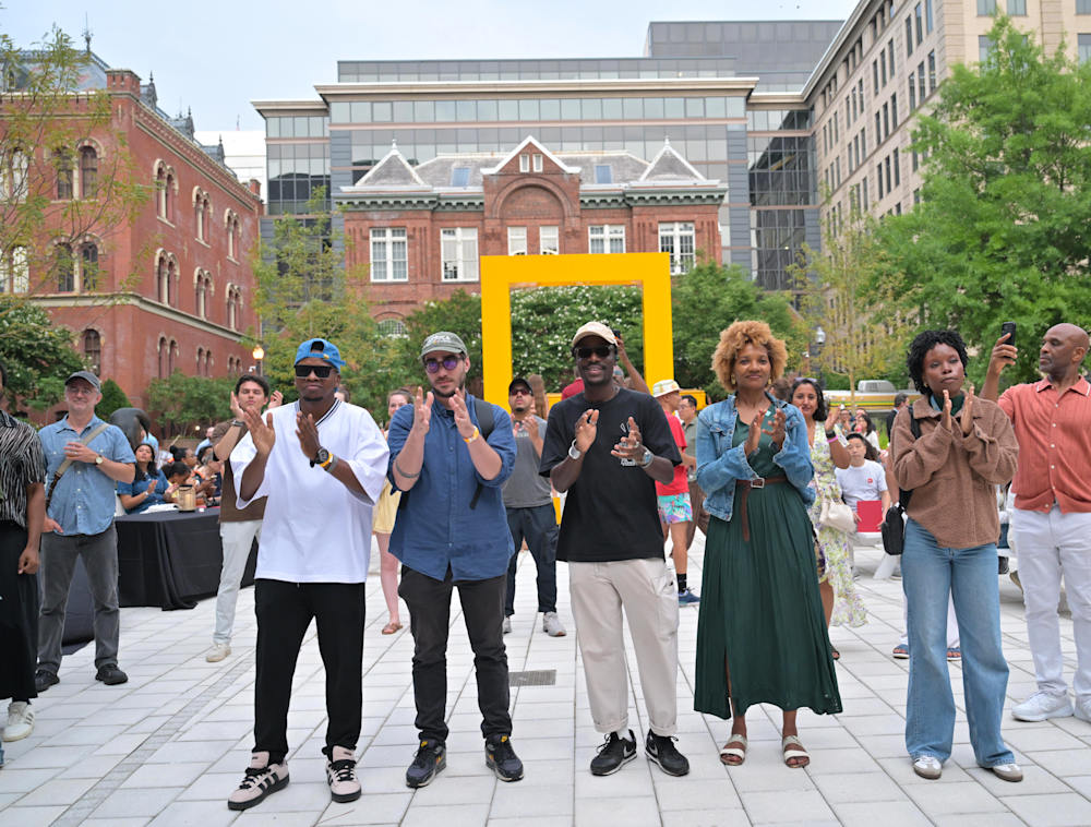 A groups of visitors clapping their hands together at the National Geographic Museum courtyard.