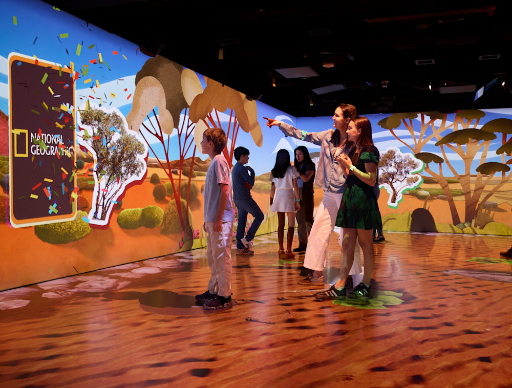 A group is immersed with visuals from scenes of one of the shows inside Geoverse. 