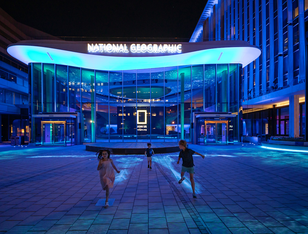 Children running in the National Geographic Museum Courtyard with the ground lighting up during the Wonders of Our World pre show.