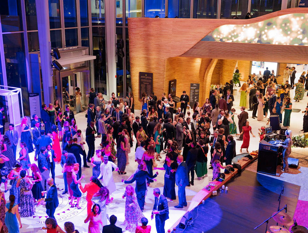 An image of the Pavilion from above. The open space is filled with partygoers dancing under colorful lights. A bare stage fills the bottom right corner of the image.