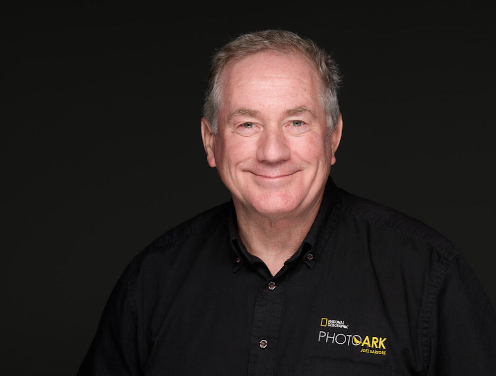 Headshot of Joel Sartore wearing a National Geographic Photo Ark shirt.