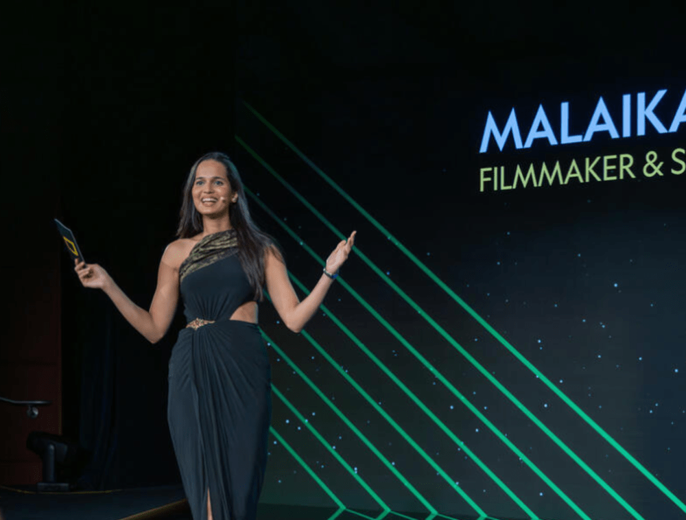 Malaika Vaz presenting on stage.