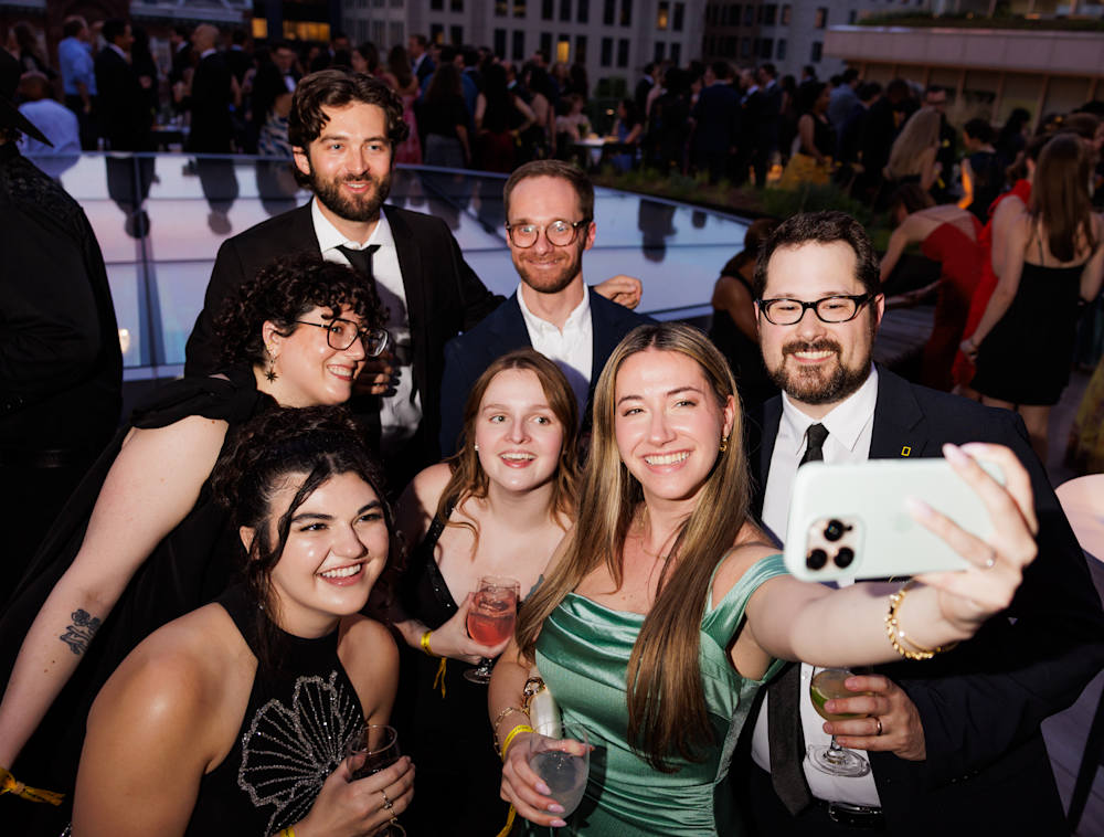 A group dressed in cocktail attire taking a selfie on the National Geographic Museum Terrace.