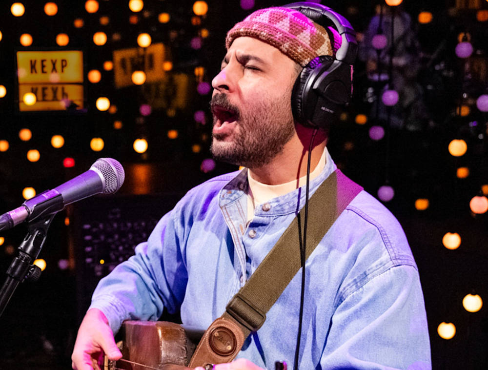 Nour Harkati performing, playing his guitar and singing.