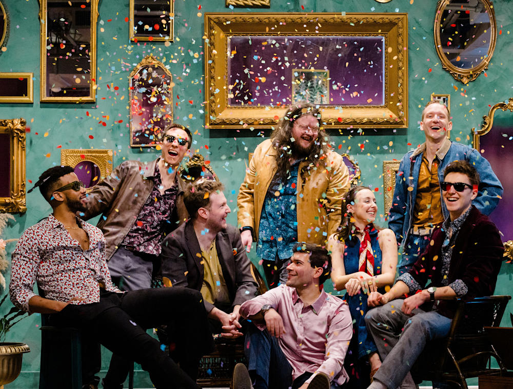 The band Strutman Lane sitting together while confetti surrounds them.
