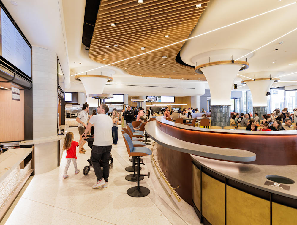 People sitting and walking around an eatery. 