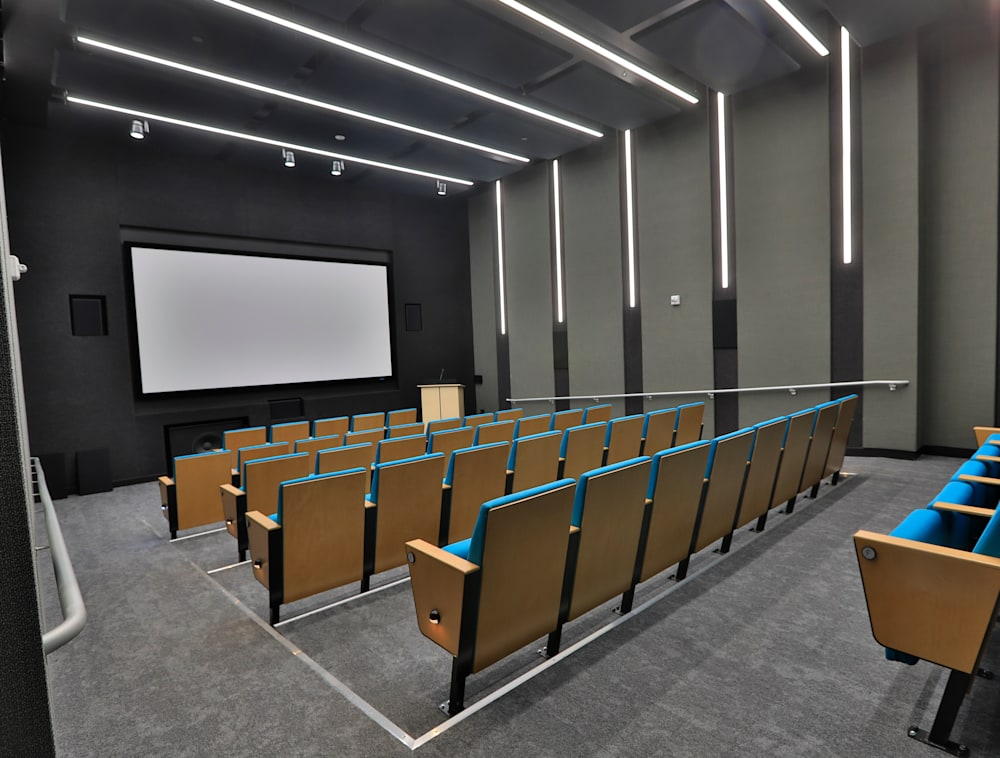 A theater room with foldable auditorium chairs and a large screen.