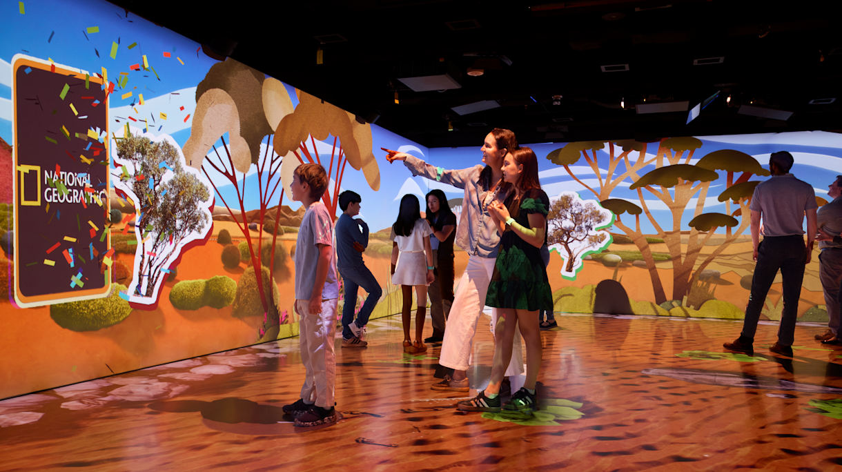 A group of people surrounded by stunning visuals inside one of the Geoverse exhibition's immersive shows. 
