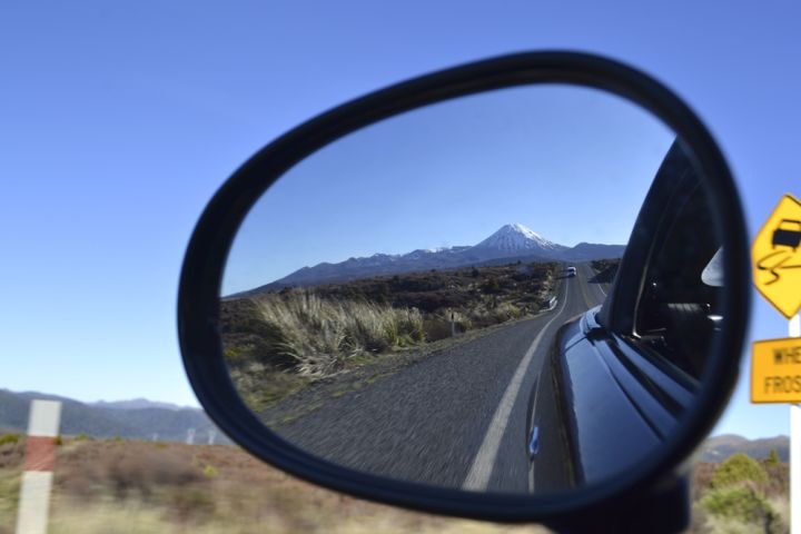 Photograph of side view mirror with mountains in the background.