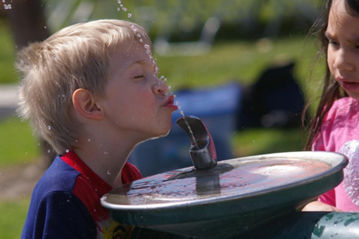 Photo of a young boy drinking from a water fountain.
