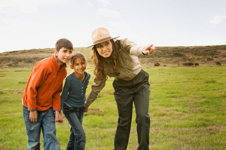 Hispanic female park ranger pointing for children