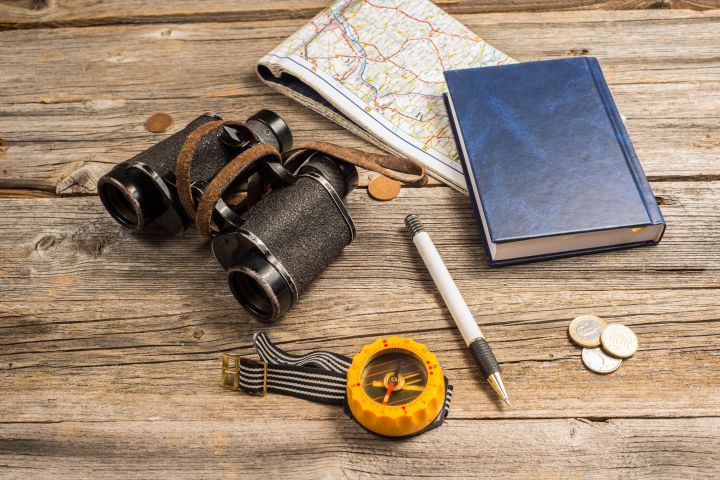 traveller equipment, items include binocullars, compass, pen, passport, map, notebook money