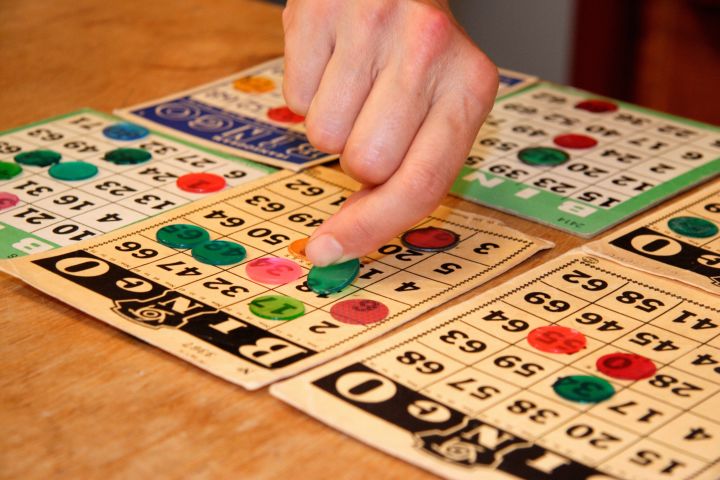 Person playing bingo, placing winning piece on bingo card, close-up