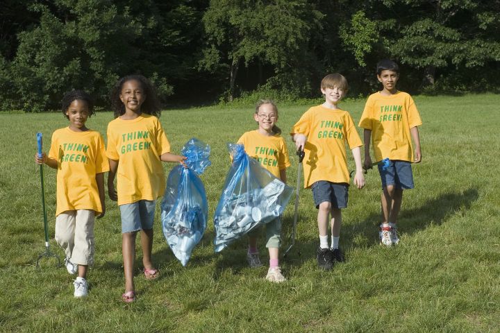Group of children (8-10) walking with garbage bags, smiling