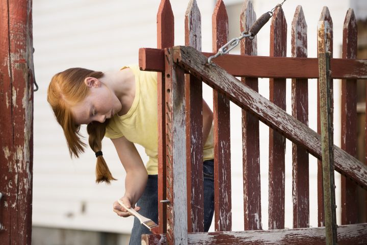 Caucasian girl painting fence