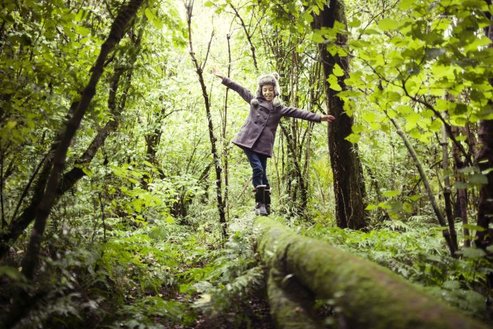 girl balancing on fallen tree