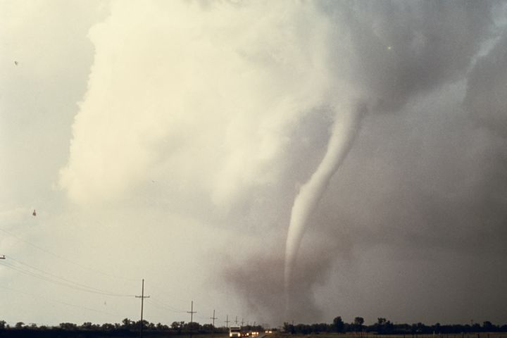 A photograph of a tornado as it touches down near a road.