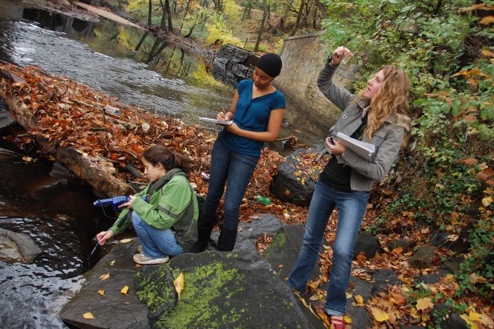 a photograph of three students sampling water in Rock Creek Park, District of Columbia.