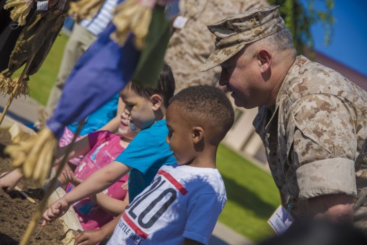 A photograph of children plant seeds with service people.