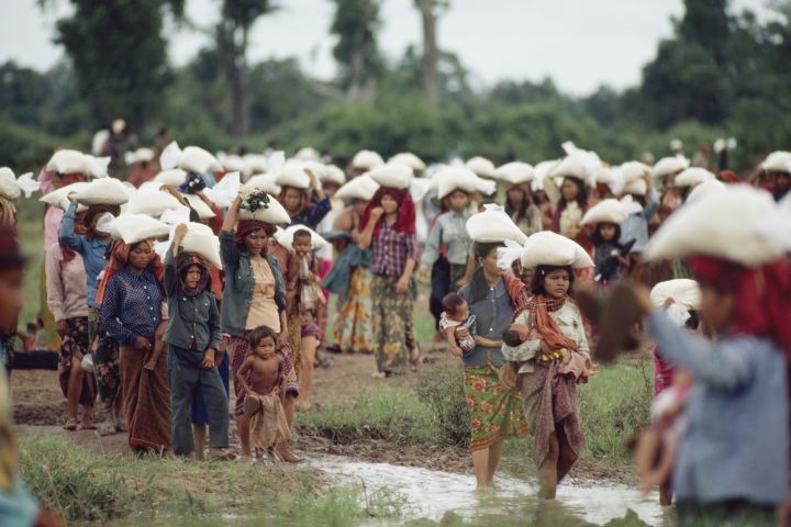 Piteous procession of homeless Cambodians carry bags of UNICEF rice.
