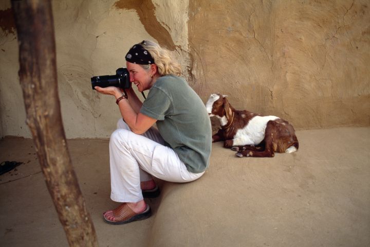Photographer Jodi Cobb frames a shot as a goat looks on.