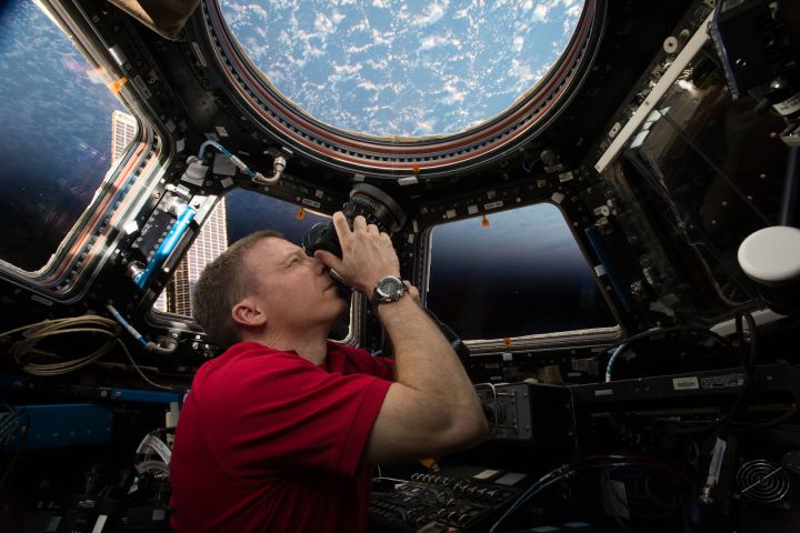 This is an image of astronaut Terry Virts taking photographs of Earth through the windows of the cupola of the International Space Station.