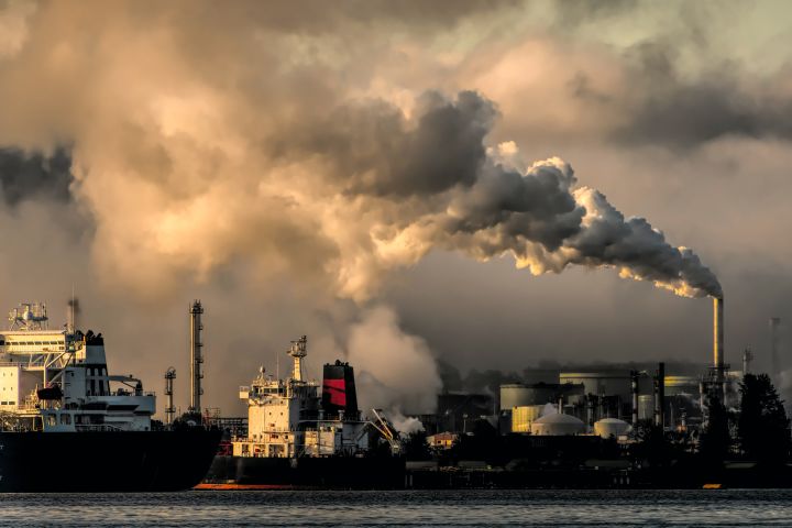 Clouds of smoke and pollutants coming from smokestacks in a shipyard