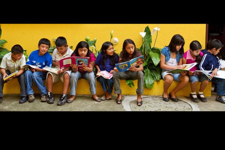 Photo: Children lined up on a step read books.