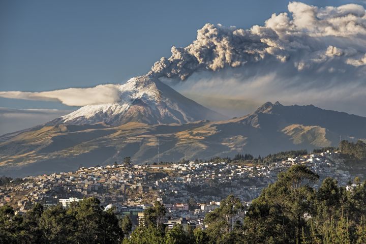 Cotopaxi volcano erupting with a town in foreground of the photo