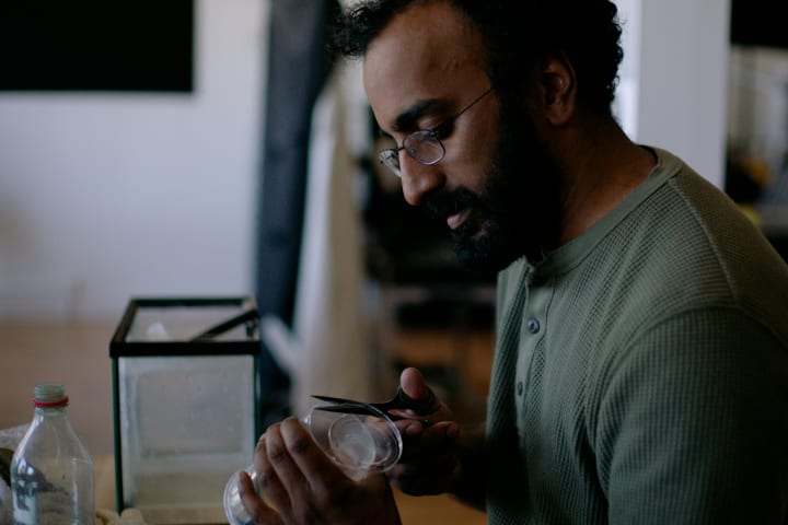 Photograph of a man using scissors to cut plastic in a laboratory.