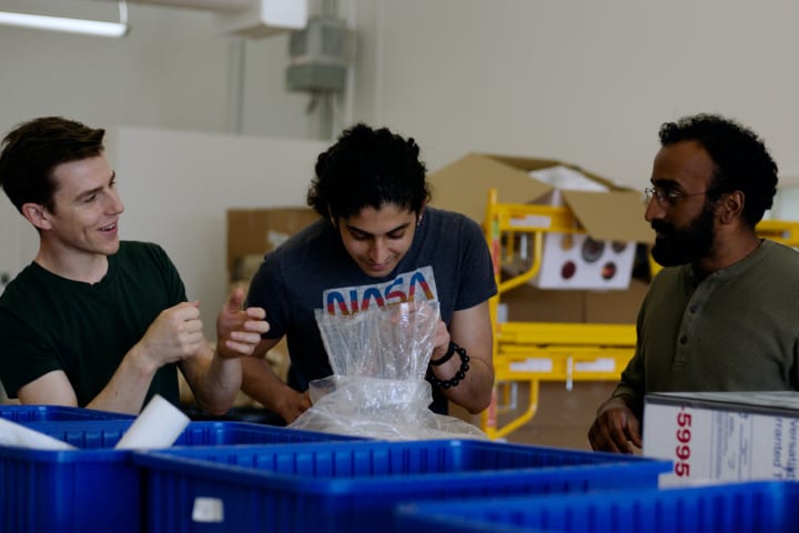 Photograph of three people doing preparation work in a laboratory.