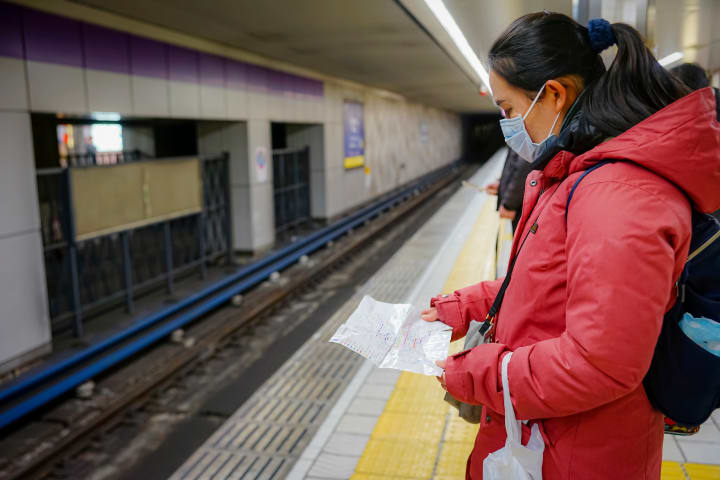 A woman looks at a map in a subway station in Japan.