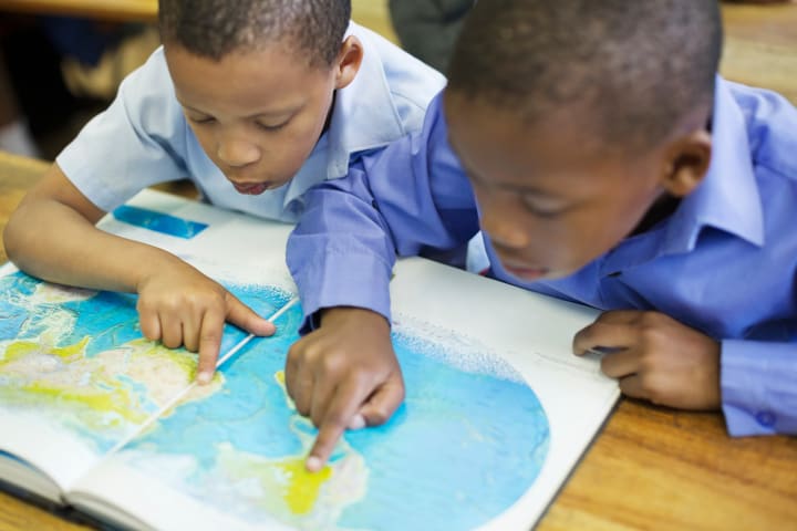 Children point to places on a map.