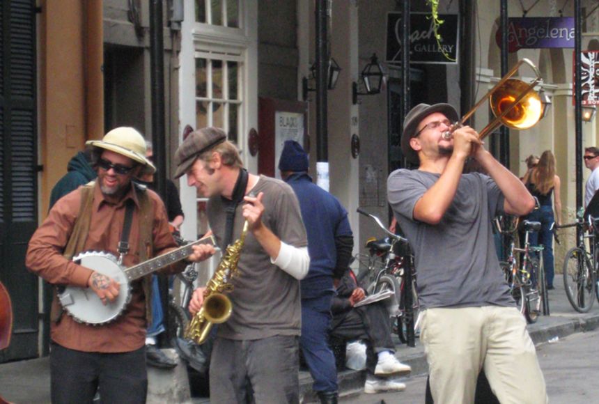 Photo: Band with banjo, saxophone, and trombone playing in the street.