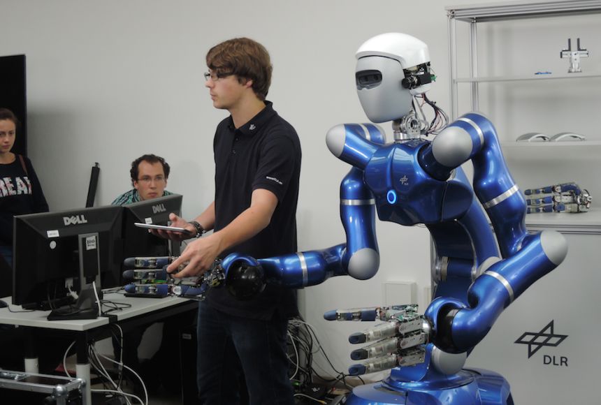 Photo of man standing next to a robot.