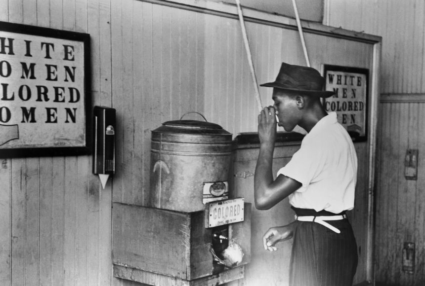 Here, an African-American man drinks from a water fountain marked "colored" at a streetcar terminal in Oklahoma City, Oklahoma in 1939.
