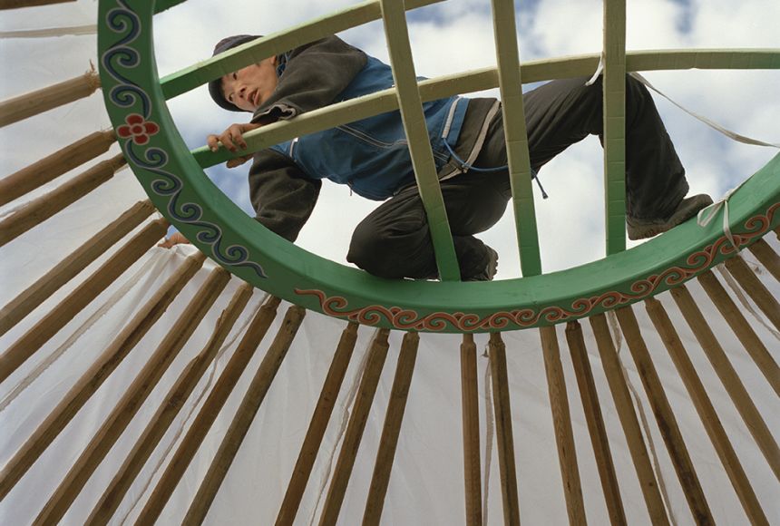 The top of a yurt with a man climbing over it