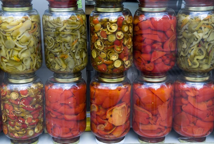 10 jars of different pickled peppers stacked on top of each other