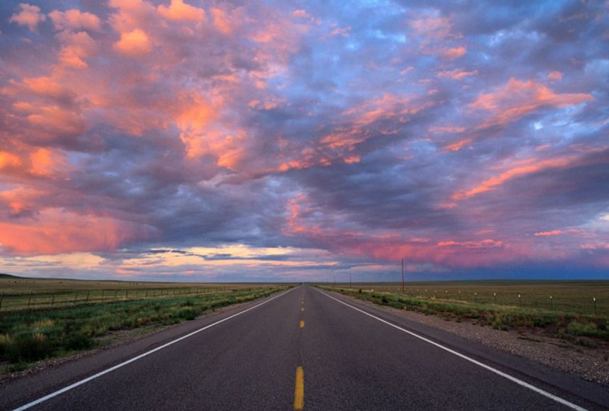 A landscape photograph of red and blue clouds hovering of the Santa Fe Trail.