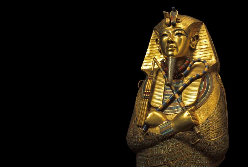 Photograph of Tutankhamen's solid-gold coffin displayed at an obtuse angle against a black background.