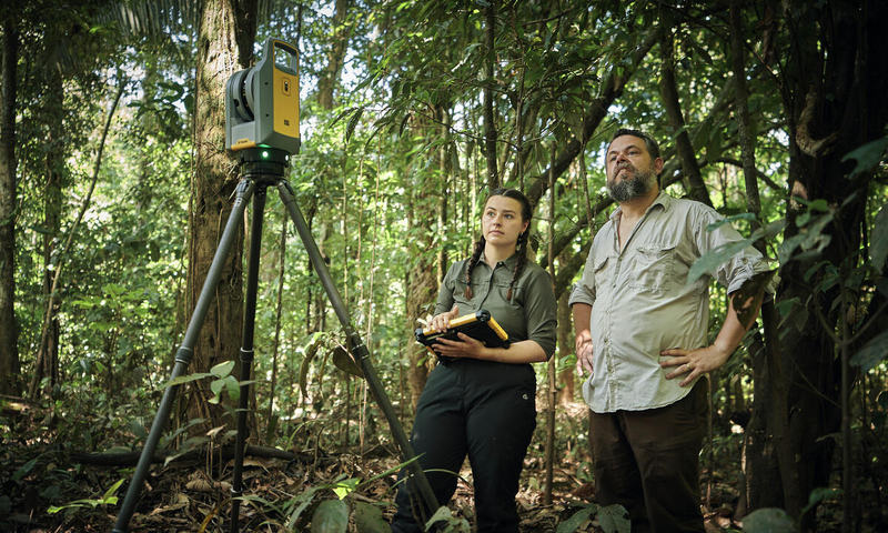 Two scientists standing in the forest using camera and scanning equipment.