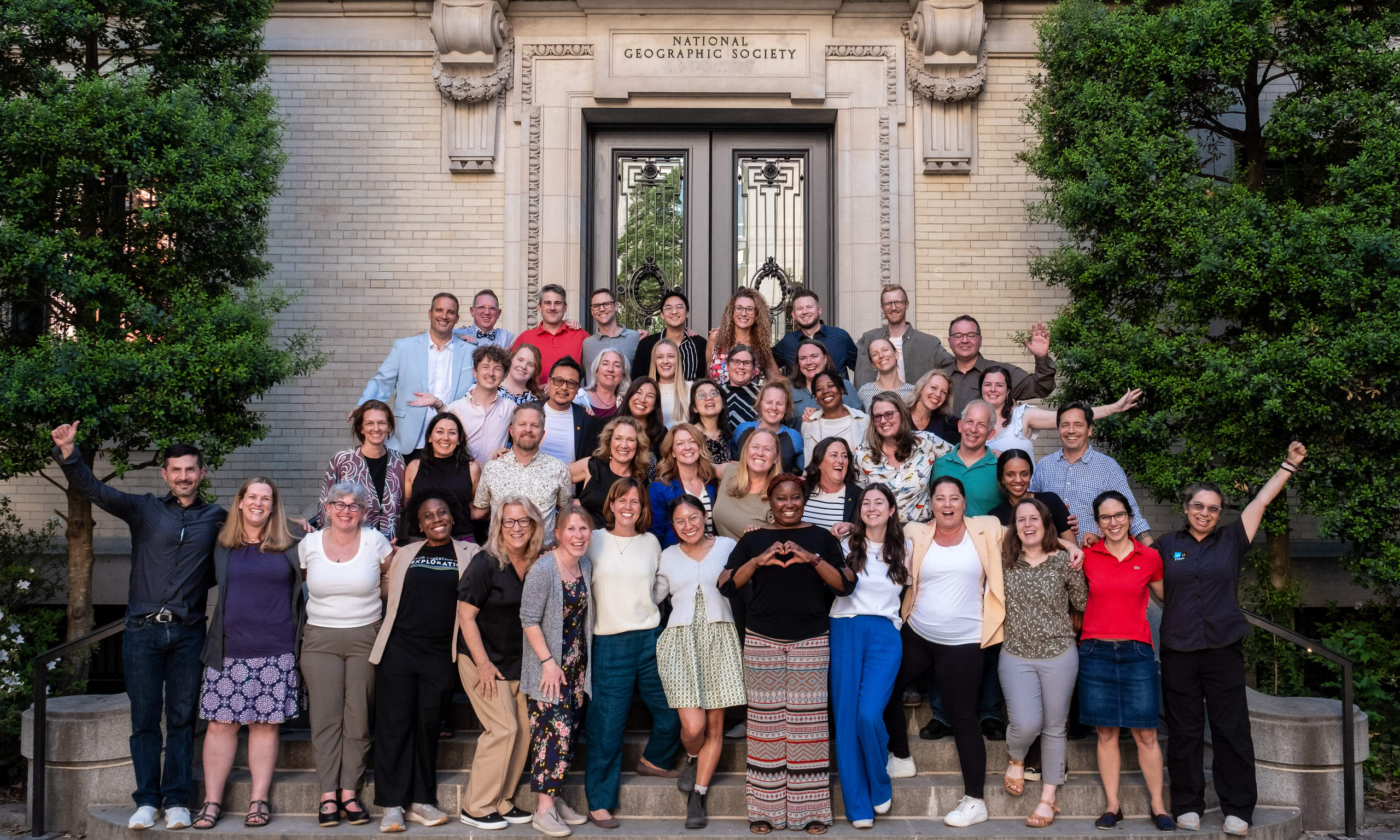 A group of educators smile and stand in front of the National Geographic Society building.
